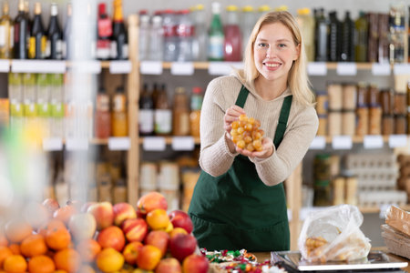 Positive female seller offers to buy delicious grapes