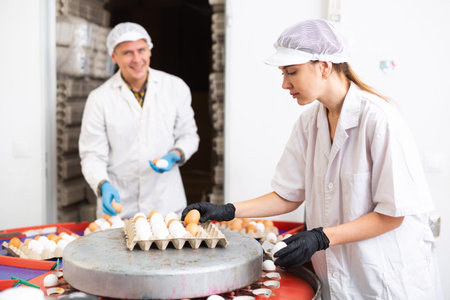 group of people in lab coats and hairnets doing egg quality control in chicken farm