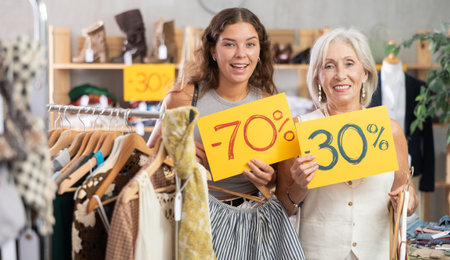 Two positive women holding sale banner in clothing storeの写真素材