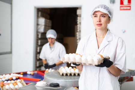 Woman holding carton tray with fresh eggs on farmの写真素材