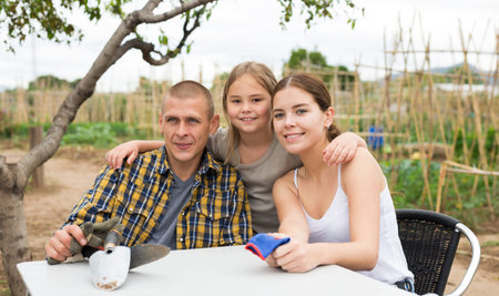 Young family resting after gardening at allotment