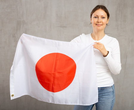 Happy woman posing with flag of Japan on gray backgroundの写真素材
