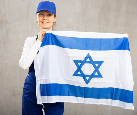 Smiling adult woman in uniform holding Israel flagの写真素材