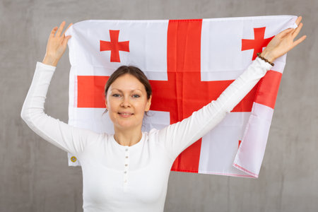 Happy smiling woman proudly displaying georgian flagの写真素材