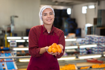 Smiling young girl working on mandarins sorting factoryの写真素材