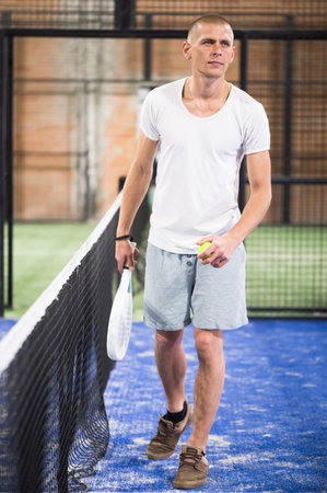 Padel player playing padel in a padel court indoor behind netの写真素材