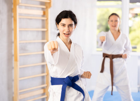 Two women training karate techniques in studioの写真素材
