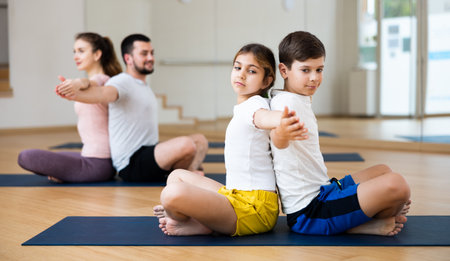 Children and parents sitting back to back on yoga matsの写真素材