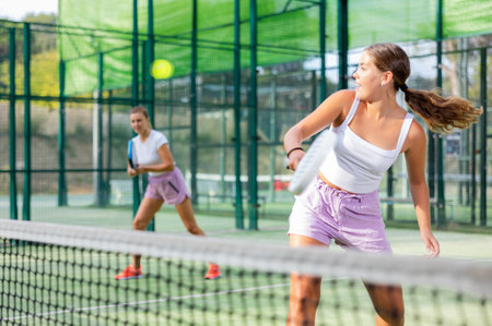 Active womans with enthusiasm playing padel on tennis courtの写真素材