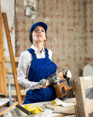 Workwoman standing at construction site with pneumatic chisel hammerの写真素材