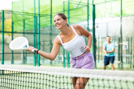Active womans with enthusiasm playing padel on tennis courtの写真素材