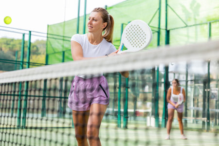 Woman in shorts playing padel tennis on courtの写真素材