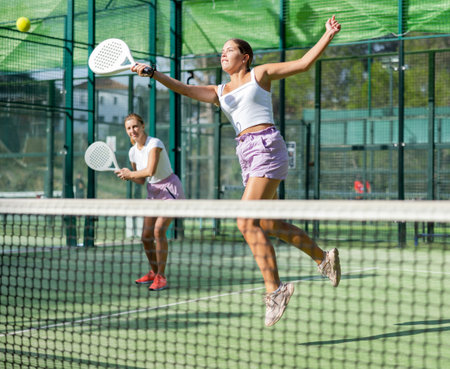Active womans with enthusiasm playing padel on tennis courtの写真素材