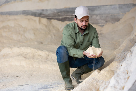 Young farmer checking quality of soy flour in livestock farm storageの写真素材