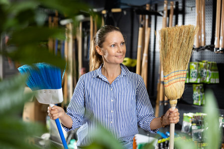 Casual woman holding two brooms while shopping in the supermarketの写真素材
