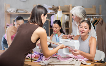 In sewing class young woman working on machine and discussing pattern