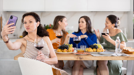 Excited woman taking selfie with besties during home celebrationの写真素材