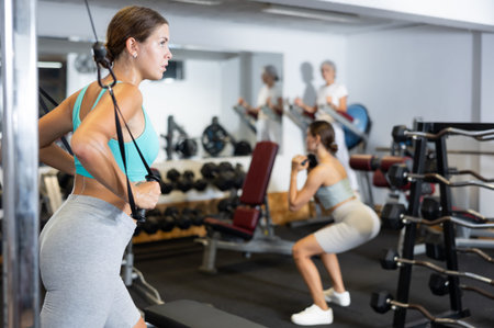 Young woman training with straps in gym
