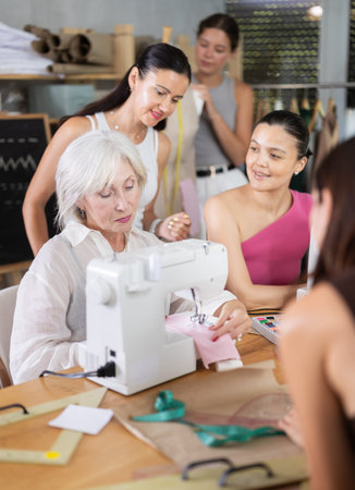 Elderly female teacher shows group how to sew