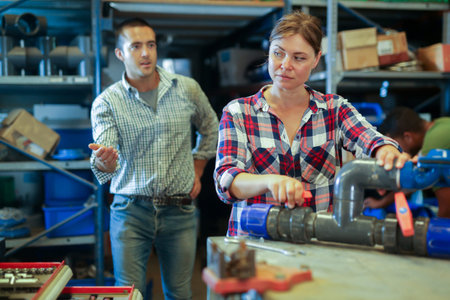Woman fixing and assembling plumbing fixture in workshop