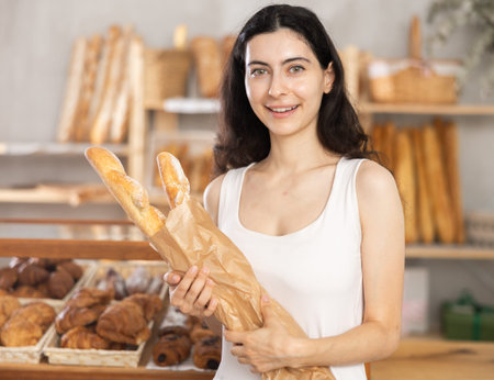 Young woman buying baguettes in bakery
