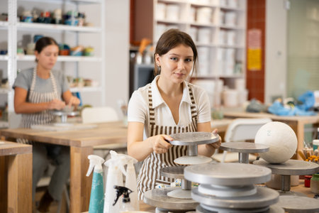 Young girl puts pottery wheel for clay modeling