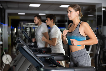 Focused girl works out with treadmill during class at fitness club