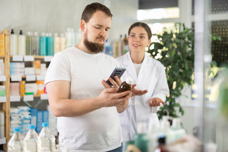 Man buyer scans syrup qr code with woman pharmacistの写真素材