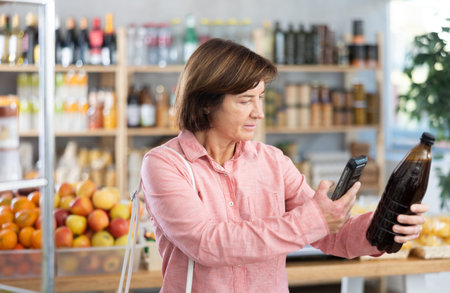 Female buyer scans QR code on beer label in grocery storeの写真素材