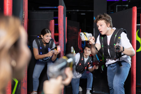 Portrait of positive man with laser gun having fun with his friends on lasertag arena