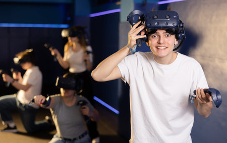 Excited young guy in VR glasses playing virtual reality game