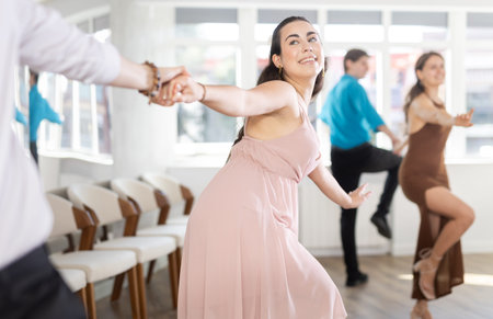Smiling girl rehearsing upbeat jive with partner in dance studio