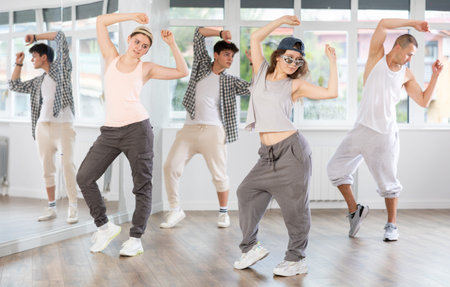 Young girl standing performs basic hip hop movements in front of group of students