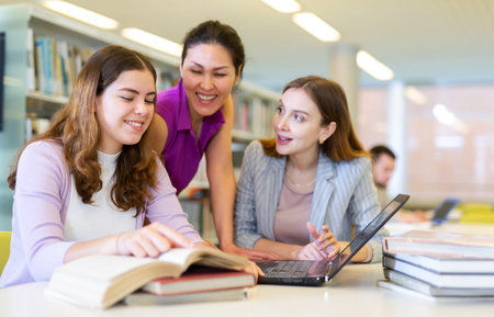 Enthusiastic female colleagues working on joint project in public library