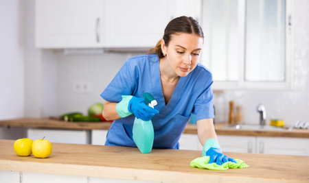 Focused cleaning service female worker at kitchen