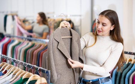 Customer deciding on demi-season coat in women cloths shop