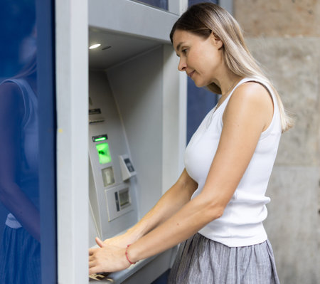 Woman uses outside ATM. Cash withdrawal, user interface