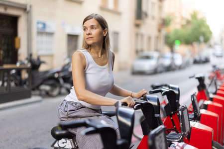 Woman rents bicycle, starts journey at parking lotのeditorial素材