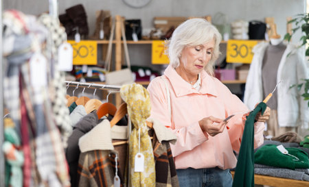 During November sales, mature woman choose and buy warm knitted dress