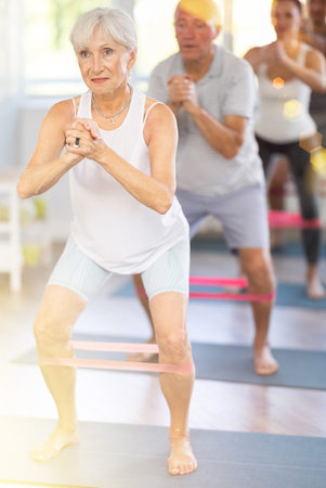 Elderly woman exercises with pilates band