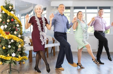 Group of elderly people with middle-aged man perform Irish folk dance during party