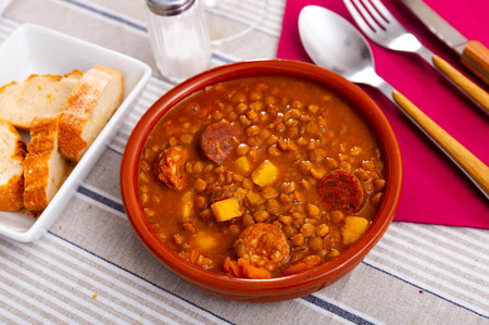Stewed lentils with chorizo and vegetables in earthenware bowlの写真素材