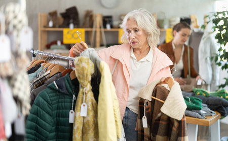 Elderly woman choosing warm coat and jackets in store