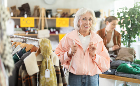 Elderly woman chooses outerwear in store