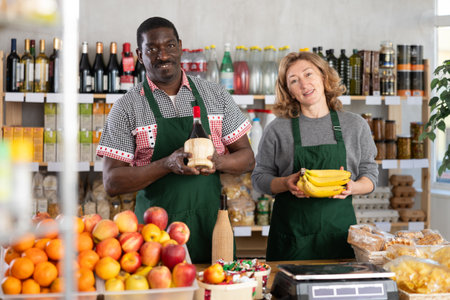 Positive female and male sellers offers choice of various natural food in grocery supermarketの写真素材