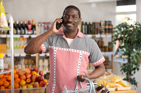 In shop African man with market basket in hands talk on phone, call friend.の写真素材