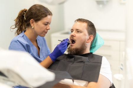Female dentist treat man teeth at dental clinicの写真素材
