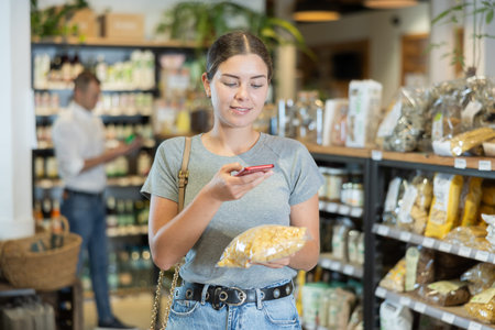 Woman scanning barcode on pasta package for mobile payment in store