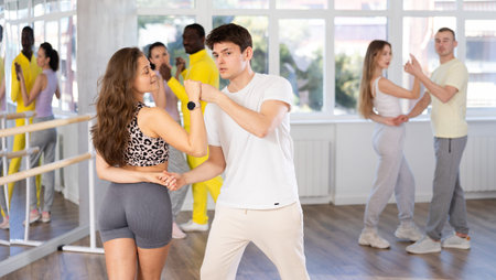Man and young woman dancing waltz in couple during lesson at studio