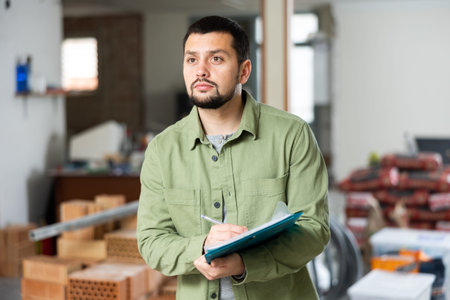 Engineer makes notes, holding a folder with documents